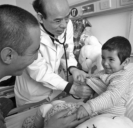 A doctor at the People's Liberation Army Air Force General Hospital in Beijing checks the health of 2-year-old Alinur Alimjan on Wednesday. Alinur, a Uygur girl from Shufu county, the Xinjiang Uygur autonomous region, was diagnosed with congenital heart disease when she was 4 months old. 