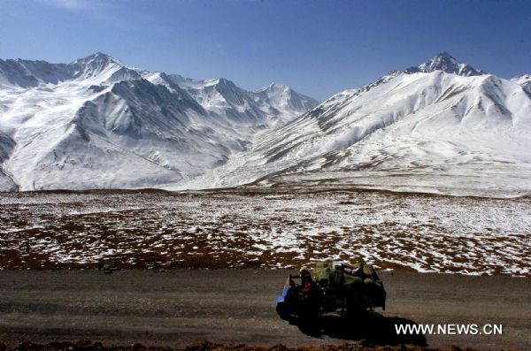 Farmers ride tractor along Qilian Mountains in northwest Gansu Province, Feb. 25, 2011. 