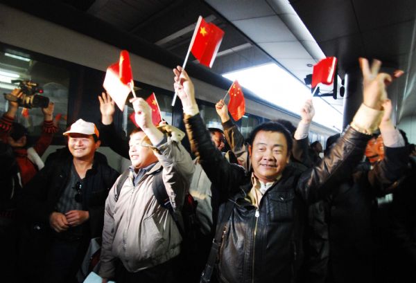 Workers from Nanchang who have been evacuated from Libya, wave flags towards the welcoming crowd after arriving at the Nanchang railway station in Nanchang, capital of east China's Jiangxi province, March 3, 2011. All together 148 Jiangxi workers, who had been evacuated to Egypt from Libya and then taken back to China by a chartered plane, arrived in Nanchang from Beijing Thursday. (Xinhua/Hu Guolin)(llp) 