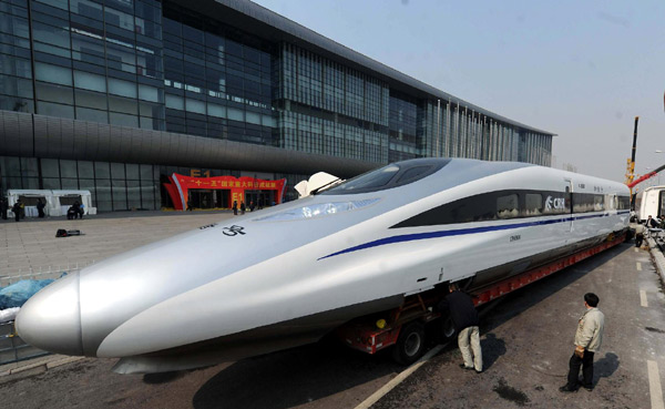 Workers at the China National Convention Center prepare to transport a locomotive of the domestically developed &apos;Harmony&apos; bullet train to the square outside the center in Beijing, March 5, 2011. The locomotive will be part of a technological achievement exhibition that opens on Monday. [Xinhua] 