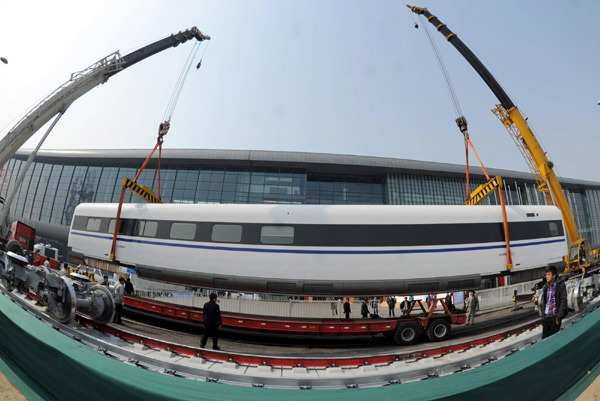 Workers at the China National Convention Center hoist parts of a bullet train to assemble it at the Center&apos;s square in Beijing, March 5, 2011. 