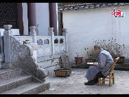A monk studies outside a temple. [by Johanna Yueh/China.org.cn]