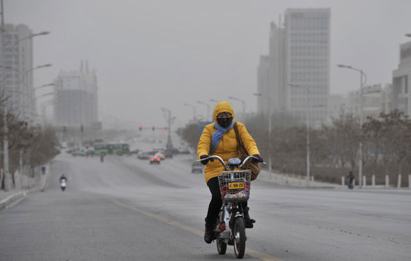 A woman rides bicycle on a street amid a sandstorm in Yinchuan, capital of Northwest China&apos;s Ningxia Hui autonomous region, March 8, 2011. [Xinhua] 