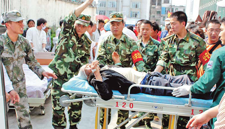 Soldiers help to give an injured man an IV drip in Yingjiang county of Yunnan province on Thursday. At least 24 people were killed and 245 injured in a 5.8-magnitude earthquake that had hit the county at 12:58 pm. [Photo/Xinhua] 