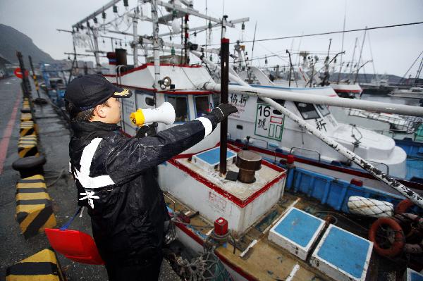 A staff member evacuates fishermen to safe area in response to a tsunami alarm in Keelung of Taiwan, southeast China, March 11, 2011. Following a strong earthquake in Japan Friday, Taiwan had earlier issued a tsunami alarm, but later sounded the all clear after foreseeing no disasters despite several small tsunamis in the afternoon. [Xinhua]