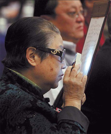 Close up: Li Shiji, a member of CPPCC National Committee, reads the document through a magnifying glass.