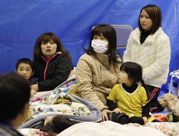 Evacuees sit through an earthquake at a temporary shelter at a stadium in Koriyama, northeastern Japan March 12, 2011. 