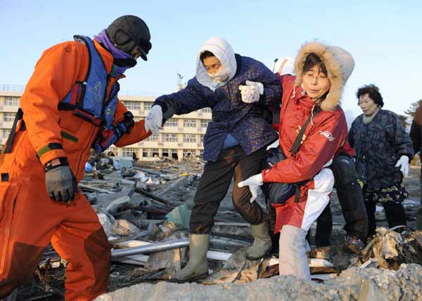 An elderly woman is assisted by rescue personnel in Sendai, northeastern Japan March 12, 2011. [Xinhua]