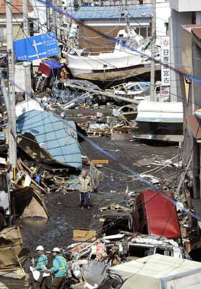 A man walks among debris and strewn boats after a tsunami in Miyako City, Iwate Prefecture in northeastern Japan March 12, 2011. [Xinhua]