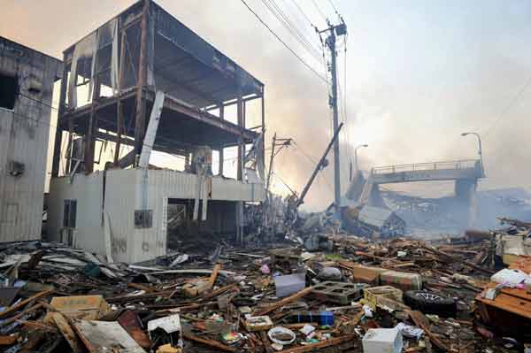 Smoke rises among buildings destroyed by a tsunami and earthquake in Miyagi Prefecture, northeastern Japan March 12, 2011. [Xinhua]