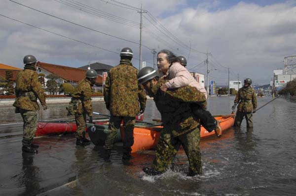 Self-Defense Force officers rescue a woman by a boat after a tsunami and earthquake in Ishinomaki City in Miyagi Prefecture March 12, 2011. Japan confronted devastation along its northeastern coast on Saturday, with fires raging and parts of some cities under water after a massive earthquake and tsunami that likely killed at least 1,000 people. [Xinhua]