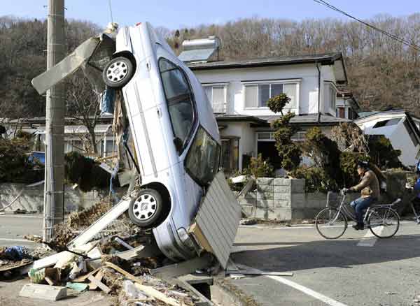 A car swept by a tsunami is overturned on the street in Miyako City, Iwate Prefecture in northeastern Japan March 12, 2011. [Xinhua]