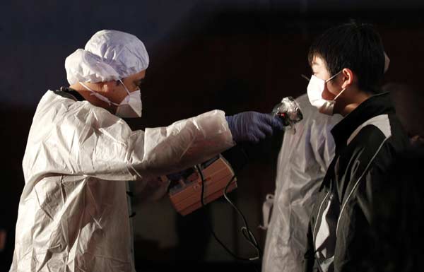 Official in protective gear scans for signs of radiation on a man who is from the evacuation area near the Fukushima Daini nuclear plant in Koriyama, March 13, 2011. [Xinhua]