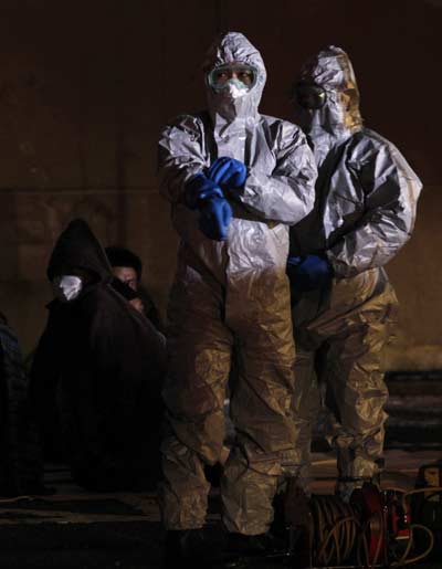 Officials in protective gear stand next to people from the evacuation area near the Fukushima Daini nuclear plant, in Koriyama, March 13, 2011. [Xinhua]