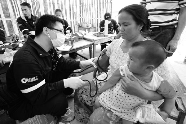 A medical volunteer from Beijing provides medical care for people from the Dai ethnic group in Hefei village, Yingjiang, Yunnan province on Sunday. After the earthquake jolted Yingjiang on Thursday, volunteers from other provinces and municipalities, including Beijing, Sichuan and Fujian, went to the quake-hit zones and took part in rescue and relief work. 