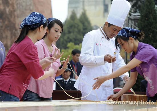 A chef surnamed Su makes the world's longest stretched noodle with his assistants, March 12, 2011.