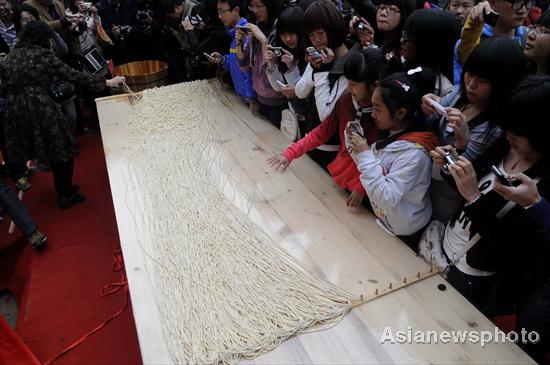 People look at the 1,704-meter-long handmade noodle at a square in Weishan county of Dali Bai autonomous prefecture, Yunnan province, March 12, 2011.