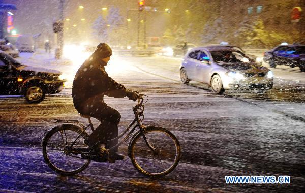 A citizen rides against snow on a street in Harbin, capital of northeast China's Heilongjiang Province, March 14, 2011. [Xinhua]