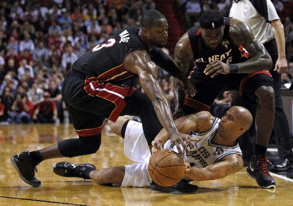 Miami Heat's Dwyane Wade (L) and LeBron James battle for a loose ball against San Antonio Spurs' Richard Jefferson (bottom) during the first quarter of NBA basketball action in Miami, Florida March 14, 2011.(Xinhua/Reuters Photo) 