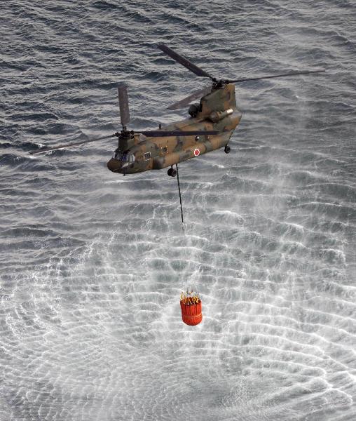 A Japan Air Self-Defense Force CH-47 Chinook helicopter collects water from the ocean to drop on the reactors at the Fukushima Daiichi nuclear plant in Fukushima March 17, 2011.[Xinhua]