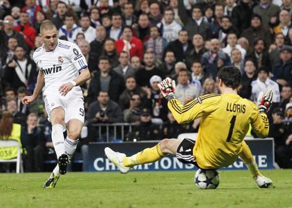 Real Madrid's Karim Benzema (L) scores past Olympique Lyon's goalkeeper Hugo Lloris during their second leg round of 16 Champions League soccer match at Santiago Bernabeu stadium in Madrid March 16, 2011. (Xinhua/Reuters Photo) 