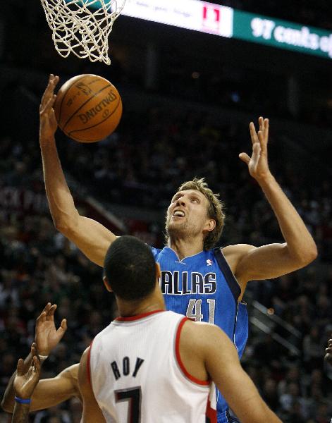 Dallas Mavericks forward Dirk Nowitzki (R) grabs a rebound as Portland Trail Blazers guard Brandon Roy looks on during the first quarter of their NBA basketball game in Portland, Oregon on March 15, 2011. Mavericks were beaten 101:104 by Trail Blazers in the regularseason game. (Xinhua/ Reuters Photo) 