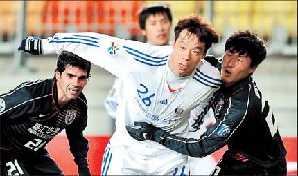 Shanghai Shenhua's Wu Xi (right) tries to hold back Suwon Bluewings' Yeom Ki-hun (center) during their AFC Champions League match in Suwon yesterday.  