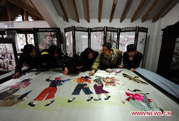 Craftsman Xiao Dequan (2nd R) introduces a Sichuan embroidery artwork to students at the Sichuan needlework museum in Chengdu, capital of southwest China's Sichuan Province, March 16, 2011. 