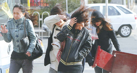 Four women struggle across a street in Beijing during the sandstorm on Friday. [China Daily] 