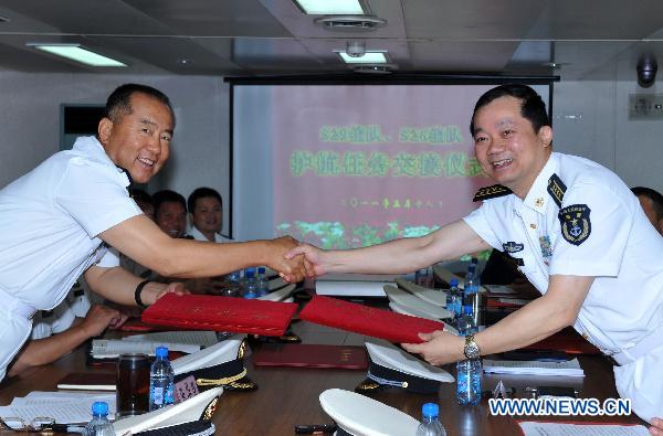 Zhang Huachen (L), commander of the seventh escort flotilla sent by the Chinese Navy to the Gulf of Aden, exchanges documents of escorting mission with Han Xiaohu, commander of the eighth escort flotilla, on the comprehensive supply ship &apos;Qiandaohu&apos; in the Gulf of Aden, March 18, 2011. 