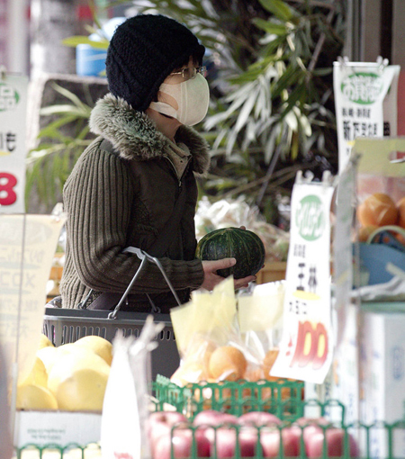 A woman purchases vegetables in a supermarket in Tokyo on March 20. Earthquake-devastated Japan announced on Saturday that radiation levels found in spinach and milk produced near the crippled Fukushima Daiichi nuclear plant exceeded safe levels. [CFP photo]
