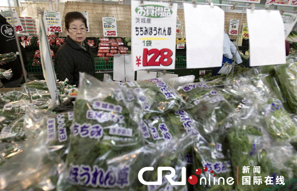 A woman purchases vegetables in a supermarket in Tokyo on March 20. The Japanese government on Monday issued an order to four prefectures near the quake-stricken Fukushima Daiichi nuclear power plant to halt shipments of certain food items due to the detection of abnormally high levels of radiation.