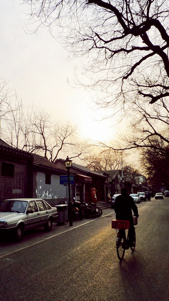 A silhouette of a stretching hutong lane rimmed by orange lights of sunset.[Photo:CRIENGLISH.com] 