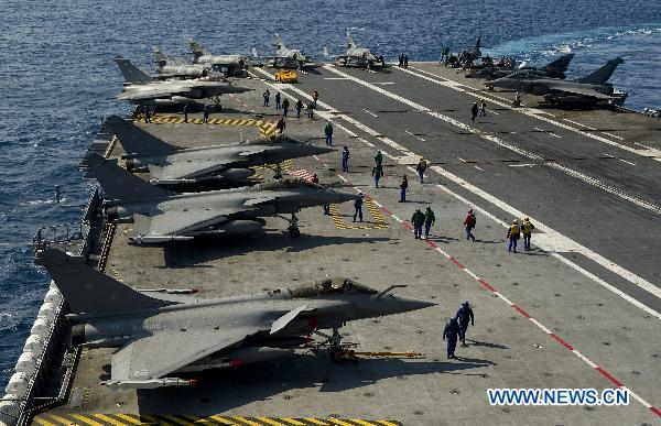 Handout photo released by ECPAD (The French Defence communication and audiovisual production agency) on March 24, 2011 shows crew members prepare prepar Rafale fighter jets for mission aboard the Charles de Gaulle aircraft carrier on March 23, 2011. [Xinhua/ECPAD]