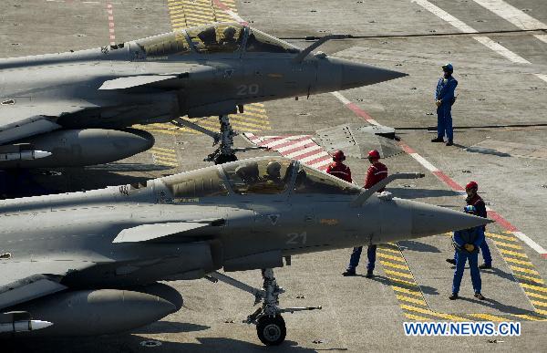 Handout photo released by ECPAD (The French Defence communication and audiovisual production agency) on March 24, 2011 shows crew members prepare prepar Rafale fighter jets for mission aboard the Charles de Gaulle aircraft carrier on March 23, 2011. [Xinhua/ECPAD]