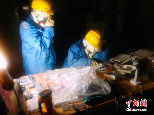 Two staff workers from the Tokyo Electric Power Company check equipment and collect data in the control room of the Fukushima Daiichi nuclear power plant on March 23, 2011. 