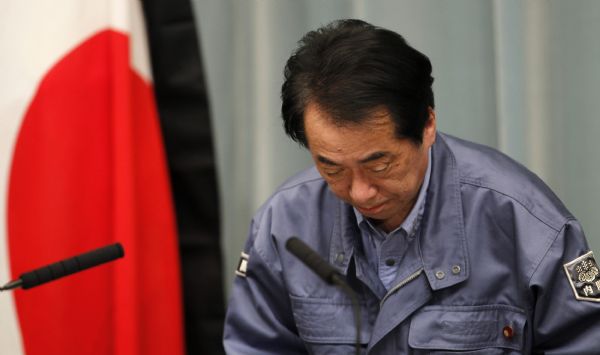 Japan's Prime Minister Naoto Kan bows in front of the Japanese flag with a black mourning cloth during a news conference at his official residence in Tokyo March 25, 2011. Kan said on Friday that the situation at a quake-damaged nuclear plant in northeast Japan remained very precarious. [Xinhua]