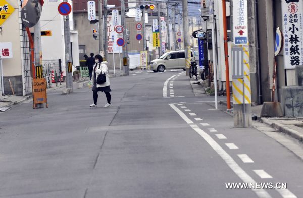 A woman crosses the street in Fukushima City, Japan, March 25, 2011. The city has been witnessing a change of people&apos;s life since the nuclear crisis broke out at the the crippled Fukushima Daiichi nuclear power plant after the earthquake. [Huang Xiaoyong/Xinhua]