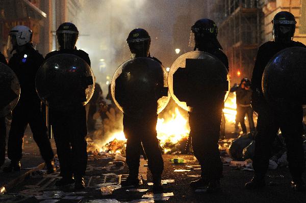 Police officers stand in front of a fire after a protest organised by the Trades Union Congress (TUC), called 'The March for the Alternative,' in central London March 26, 2011. (Xinhua/Reuters Photo) 