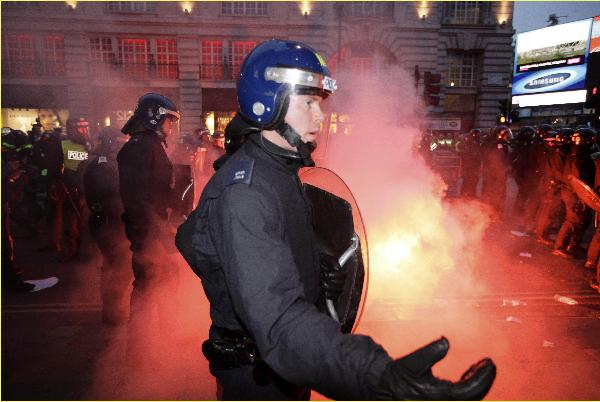 Police confront demonstrators, as a flare burns on the ground, in Piccadilly Circus, after a protest organised by the Trades Union Congress (TUC), called 'The March for the Alternative,' in central London March 26, 2011. (Xinhua/Reuters Photo)