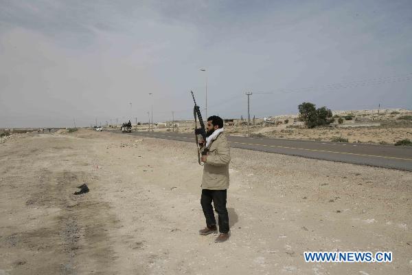 A Libyan rebel searchs for Moammar Gadhafi's forces near Ras Lanuf, eastern Libya, March 27, 2011. The rebels claim that they have entered Ras Lanuf on Sunday. [Nasser Nouri/Xinhua]