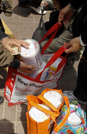 People pack Japanese milk powder containers into shopping bags in Hong Kong two days after the earthquake in Japan. The threat of nuclear radiation leaks from a damaged plant have stoked Chinese concerns about food supplies from Japan. [China Daily via agencies]