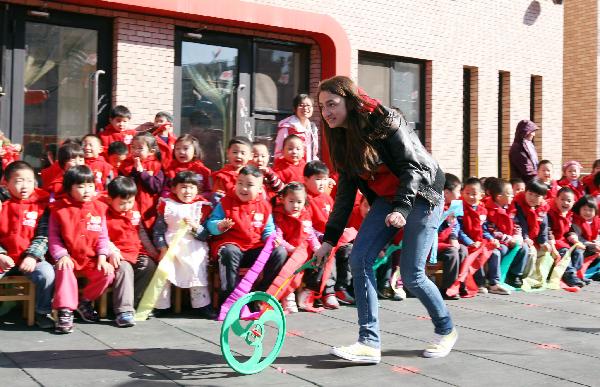 A student of Sweden plays hoop rolling during an international folk games festival in a kindergarten in Beijing, capital of China, March 24, 2011. Over ten Swedish middle school students joined the festival to experience Chinese traditional games with the children and teachers of the kindergarten.