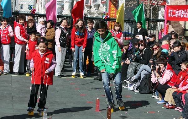 A Swedish student (Right, C) attends walking race with a pair of stilts during an international folk games festival in a kindergarten in Beijing, capital of China, March 24, 2011. Over ten Swedish middle school students joined the festival to experience Chinese traditional games with the children and teachers of the kindergarten.