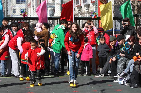 A Swedish student (Right, C) attends walking race with a pair of stilts during an international folk games festival in a kindergarten in Beijing, capital of China, March 24, 2011. Over ten Swedish middle school students joined the festival to experience Chinese traditional games with the children and teachers of the kindergarten. 