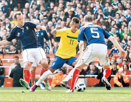 Brazil's Neymar (center) is tackled by Scotland's Charlie Adam (left) which resulted in a penalty. Neymar scored a brace to guide his team to a 2-0 win during an international friendly match in London on Sunday.  