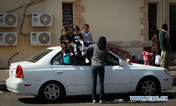 A boy waits for food and water at Egyptian border crossing of Sallum, March 29, 2011. Thousands of refugees have gathered near the border of Libya and Egypt to flee the violence in Libya and wait for the help from international organizations.[Cai Yang/Xinhua]