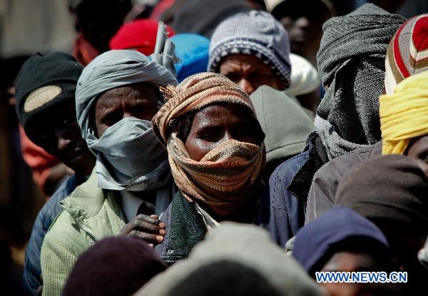 Refugees wait for food and water at Egyptian border crossing of Sallum, March 29, 2011. Thousands of refugees have gathered near the border of Libya and Egypt to flee the violence in Libya and wait for the help from international organizations.[Cai Yang/Xinhua]