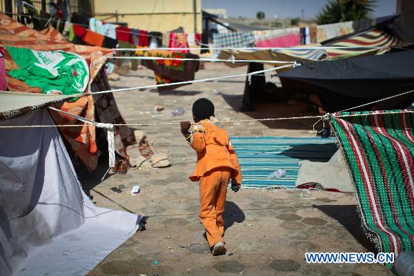 A boy plays at a refugee camp near the Egyptian border crossing of Sallum, March 29, 2011. Thousands of refugees have gathered near the border of Libya and Egypt to flee the violence in Libya and wait for the help from international organizations.[Cai Yang/Xinhua]