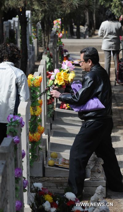 A man is seen holding a bunch of flowers in a cemetery in Beijing, capital of China, March 26, 2011, a few days ahead of China's traditional tomb-sweeping day on which Chinese memorized their beloved ones, on April 5th this year. [Li Wen/Xinhua]